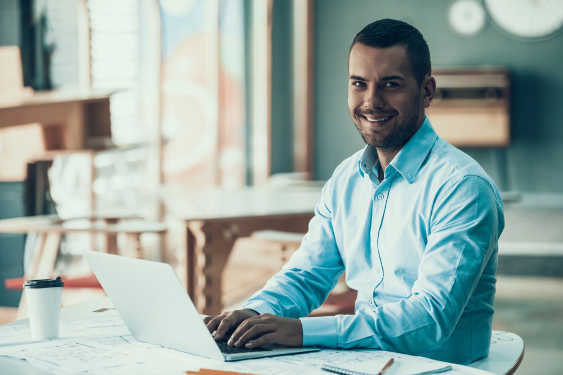 Développeur souriant travaillant sur un ordinateur portable – Illustration de la conformité RGPD dans le développement d’applications mobiles.