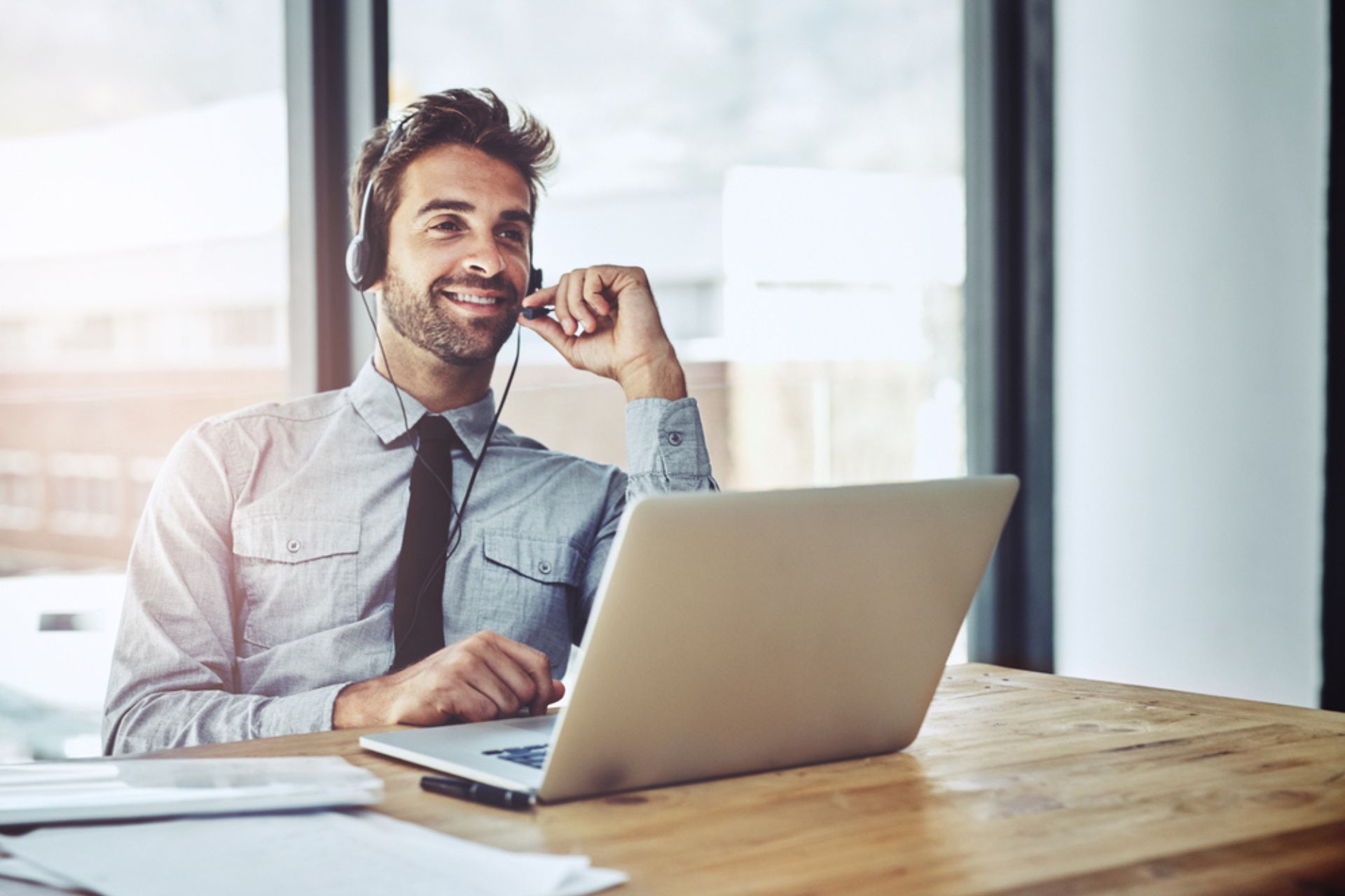 Homme d'affaires souriant en visioconférence, travaillant sur un ordinateur portable dans un bureau moderne – illustration du rôle du DPO dans la conformité RGPD.