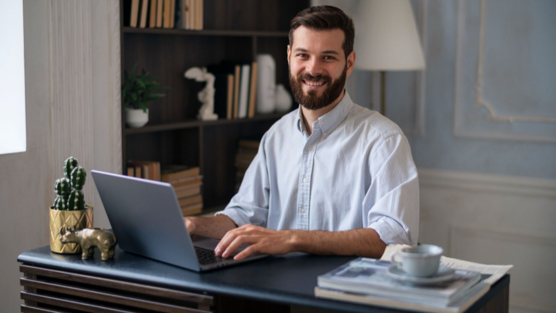 Homme souriant travaillant sur un ordinateur portable dans un bureau moderne, représentant la gestion des candidatures et le respect du RGPD